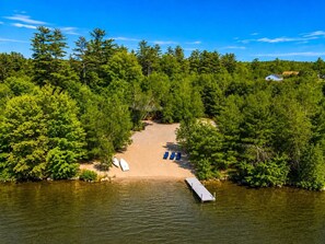 A lakeside cabin with a dock, surrounded by dense forest.