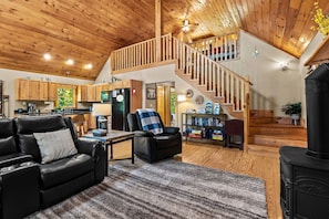 A spacious living area with a fireplace, a sofa, a recliner, and a staircase leading to an upper level.