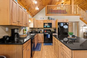 A modern kitchen with wooden cabinets, a black countertop, and a built-in oven.