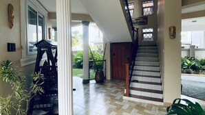 A spacious foyer with a checkered floor, a staircase, and a large column. - New and stylish 3-Bedroom Apartment (Dar es Salaam)