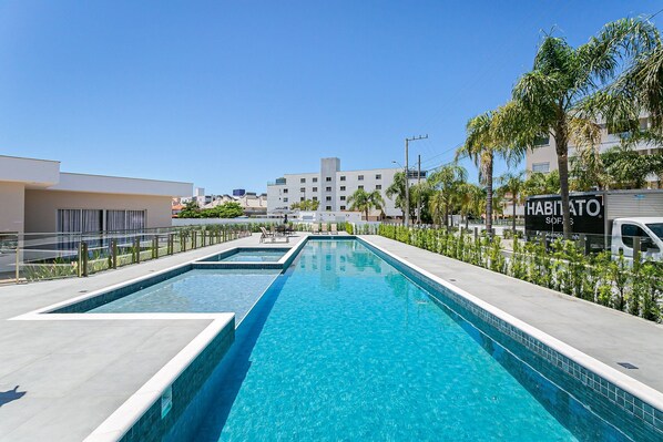 Ett modernt hotell med en swimmingpool, en skylt med texten ”Habito Soi” och utsikt över stadsbilden.