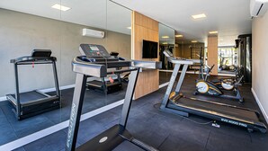Un gimnasio moderno con cintas de correr, elípticas y una bicicleta estática.