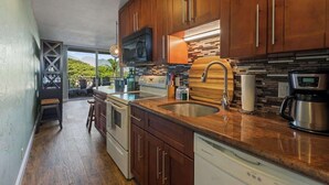 A modern kitchen with wooden cabinets, a stainless steel sink, and a built-in microwave. - Oceanview updated 1 bedroom condo, AC, 6 mile sandy beach (Kihei)