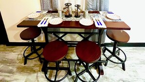 Un coin repas avec une table dressée pour quatre personnes, comprenant des assiettes, des couverts et des verres.