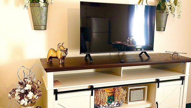 Un meuble pour télévision avec un téléviseur à écran plat, des objets décoratifs et une enseigne placée au-dessus.