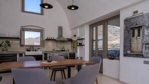 Una cocina moderna con una gran mesa de comedor, sillas grises y vistas a las montañas a través de las ventanas.