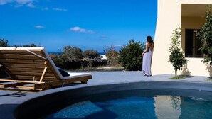 Zona de piscina con una silla de descanso y una persona de pie junto a la piscina.