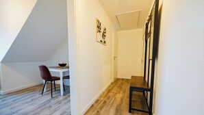 A narrow hallway with a wooden floor, a white door, and a dining area with a table and chairs. - Central feel-good apartment 1 - ideal for your vacation or business trip (Magdeburg)