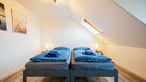 A room with two beds, a skylight, and a wooden floor. - Central feel-good apartment 1 - ideal for your vacation or business trip (Magdeburg)