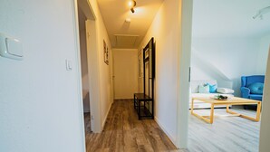 A hallway with wooden flooring leading to a living area with a sofa and a coffee table. - Central feel-good apartment 1 - ideal for your vacation or business trip (Magdeburg)