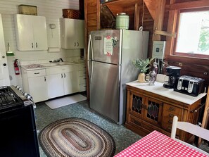 Eine kleine Küche mit weißen Schränken, einem Edelstahlkühlschrank, einer Kaffeemaschine und einem Toaster auf der Arbeitsfläche.