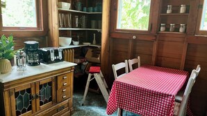 A compact kitchen with wooden cabinets, a coffee maker, and a red checkered tablecloth-covered table. - Charming 5-bedroom Roaring Brook cottage in Harbor Springs with beach access. (Harbor Springs)