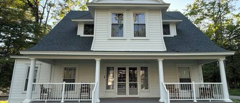 A two-story house with a porch, a chimney, and a front door.