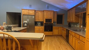 Une cuisine avec des meubles en bois, un réfrigérateur en acier inoxydable, un four à micro-ondes et un four traditionnel.