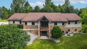 Une maison à deux étages avec une façade en pierre, une grande véranda à l’avant et un garage.