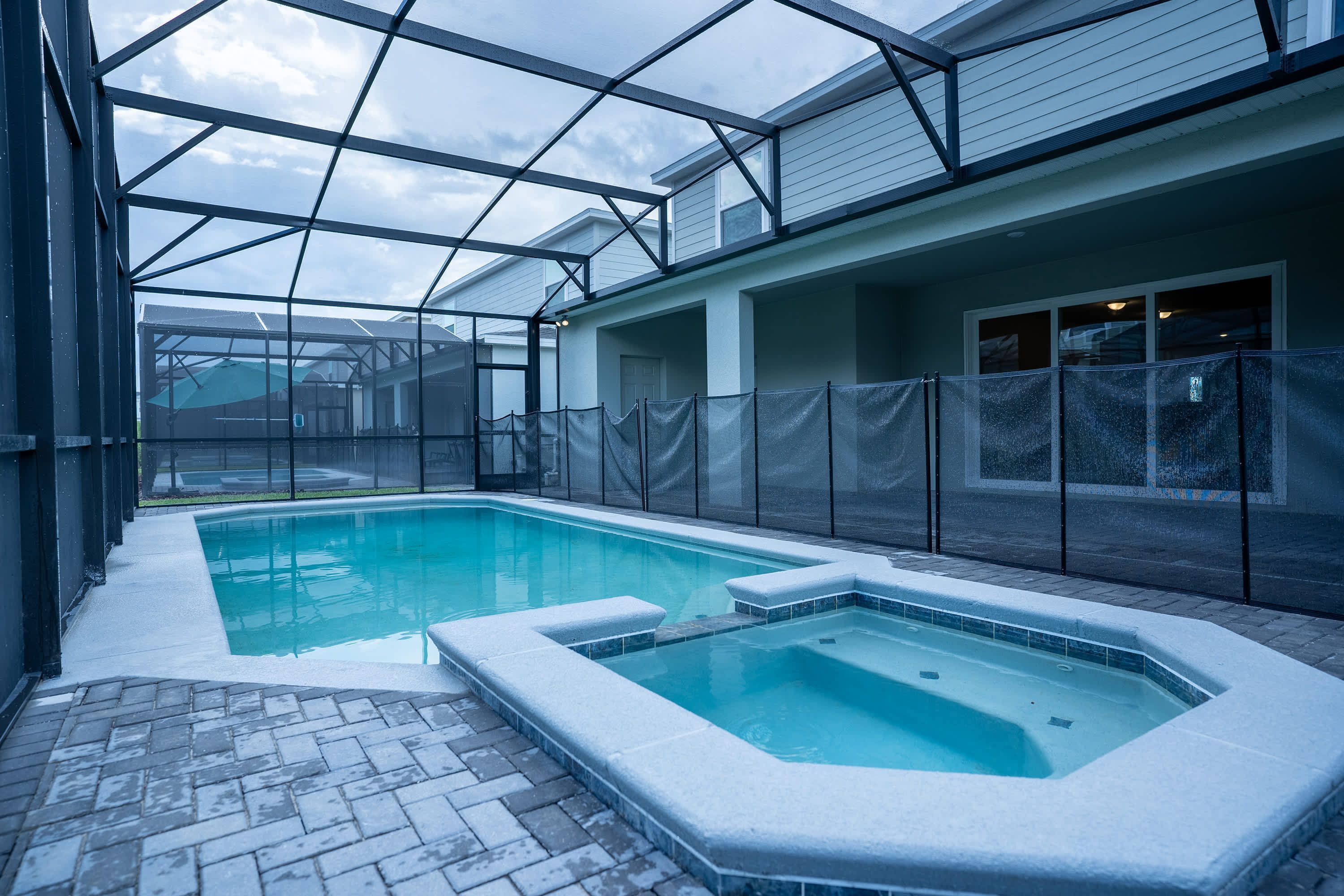Ein Pool mit Whirlpool, umgeben von einer überdachten Terrasse mit Glasdach.