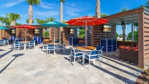 An outdoor patio area with stone flooring, wooden pergolas, and tables with chairs. - Fun and Relax 10 Bed Home Pool Themed Rooms (Clermont)