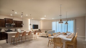 A spacious kitchen with modern appliances, a dining area with a large table and chairs, and a living area with a sofa and TV. - Fun and Relax 10 Bed Home Pool Themed Rooms (Clermont)