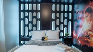 A modern bedroom with a large bed, a decorative headboard, a poster on the wall, and a nightstand with a lamp and a small plant. - Fun and Relax 10 Bed Home Pool Themed Rooms (Clermont)