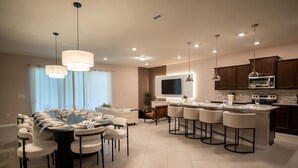 Una cucina moderna con isola centrale, elettrodomestici integrati e luci a sospensione.