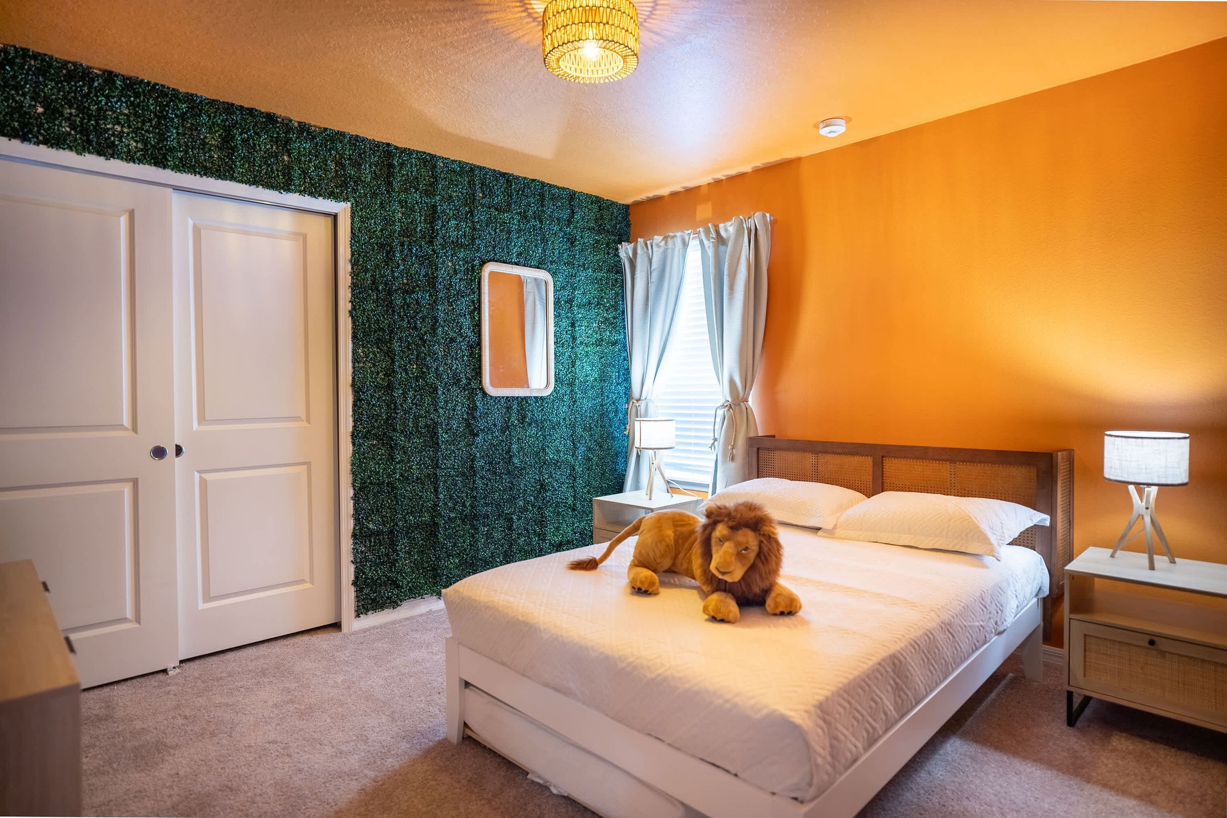 Ein Schlafzimmer mit einem Bett, einem Spiegel, einem Nachttisch und einer grünen Wand.