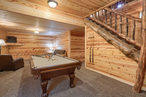 A wooden-paneled room with a pool table, a sofa, and a staircase. - Waccabuck | 17.5 Private Acres, Pool, Hot Tub (Logan)