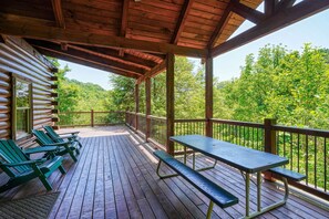 A wooden deck with a picnic table and chairs, overlooking a forested area. - Waccabuck | 17.5 Private Acres, Pool, Hot Tub (Logan)