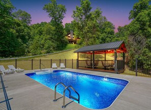 A swimming pool with lounge chairs, a covered seating area, and a view of a house in the background. - Waccabuck | 17.5 Private Acres, Pool, Hot Tub (Logan)