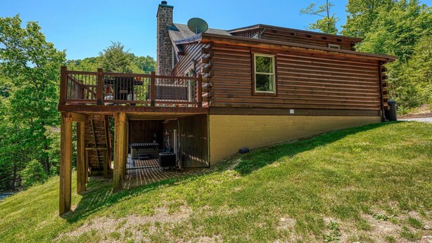Une cabane en rondins avec une terrasse, une cheminée et une antenne parabolique.