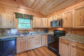 A wooden cabin-style kitchen with granite countertops, wooden cabinets, a dishwasher, a microwave, and an oven. - Waccabuck | 17.5 Private Acres, Pool, Hot Tub (Logan)