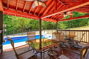 A covered outdoor area with a pool, wooden deck, and seating.