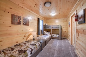 A cabin with two bunk beds, a small table with a lamp, and wooden walls with animal paintings. - Sandstone Valley Estate | Hocking, Indoor Pool (Logan)