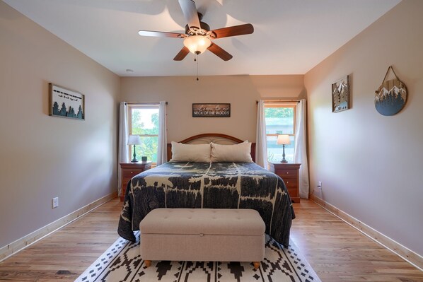 A bedroom with a bed, a ceiling fan, two nightstands, a bench, and a rug. - Sandstone Valley Estate | Hocking, Indoor Pool (Logan)
