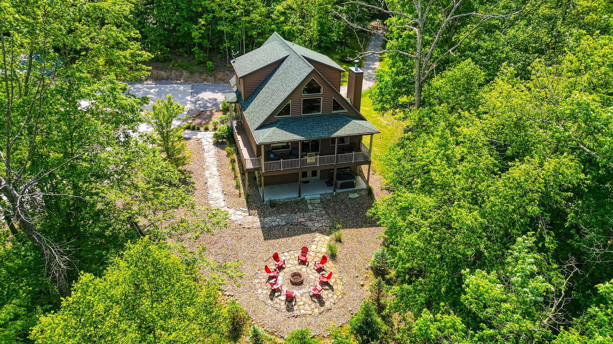 A cabin with a stone patio and a fire pit surrounded by chairs.