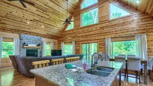 A spacious kitchen with granite countertops, a stone fireplace, and a bar area. - Sandstone Valley Estate | Hocking, Indoor Pool (Logan)