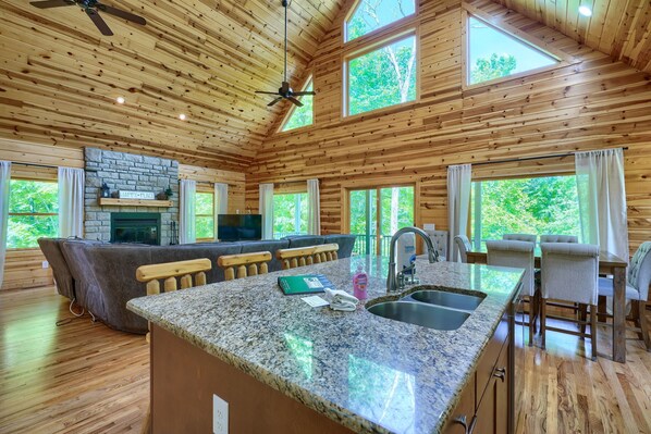 A spacious kitchen with granite countertops, a stone fireplace, and a bar area.