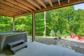 Une terrasse en bois avec un jacuzzi, une table de pique-nique et des fauteuils Adirondack rouges.
