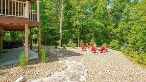 A wooden deck with a ceiling fan, a stone pathway, and red Adirondack chairs in a forested area. - Sandstone Valley Estate | Hocking, Indoor Pool (Logan)