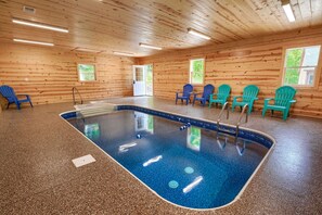 A wooden interior with a pool, blue chairs, and a door leading outside.