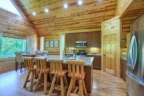 L’intérieur d’un chalet en bois comprend une cuisine, un coin repas et de grandes fenêtres.