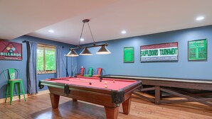 A pool table in a room with blue walls, a billiards championship sign, and a shuffleboard tournament sign. - Sandstone Valley Estate | Hocking, Indoor Pool (Logan)