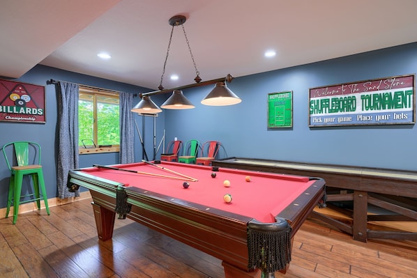 A pool table with billiard balls, a green chair, and a sign for a shuffleboard tournament. - Sandstone Valley Estate | Hocking, Indoor Pool (Logan)