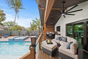 A poolside area with a wooden deck, outdoor furniture, and a ceiling fan. - Luxurious "Villa Nella" (Naples)