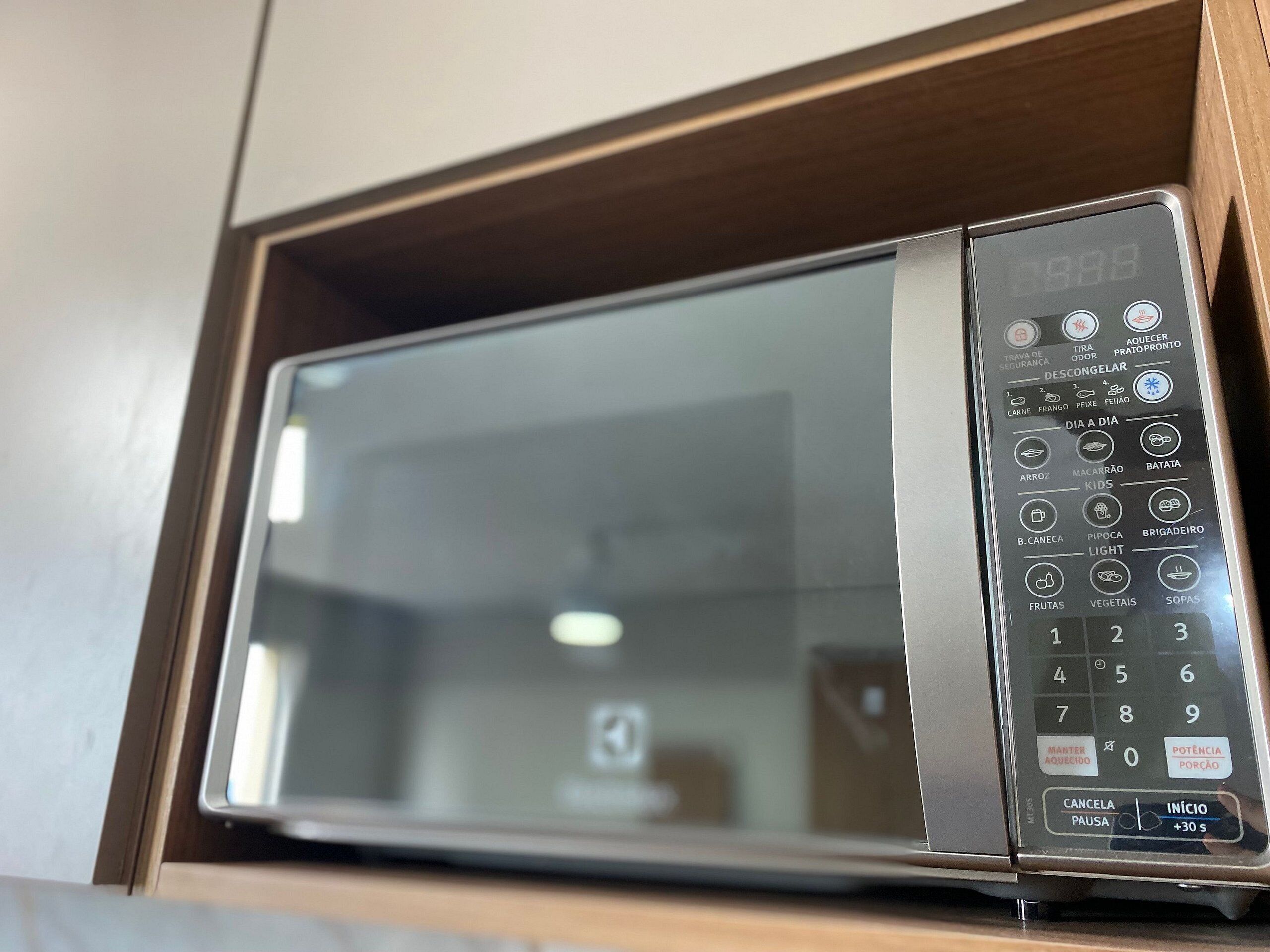 Een magnetron met een digitaal display, bedieningspaneel en een houten kast.