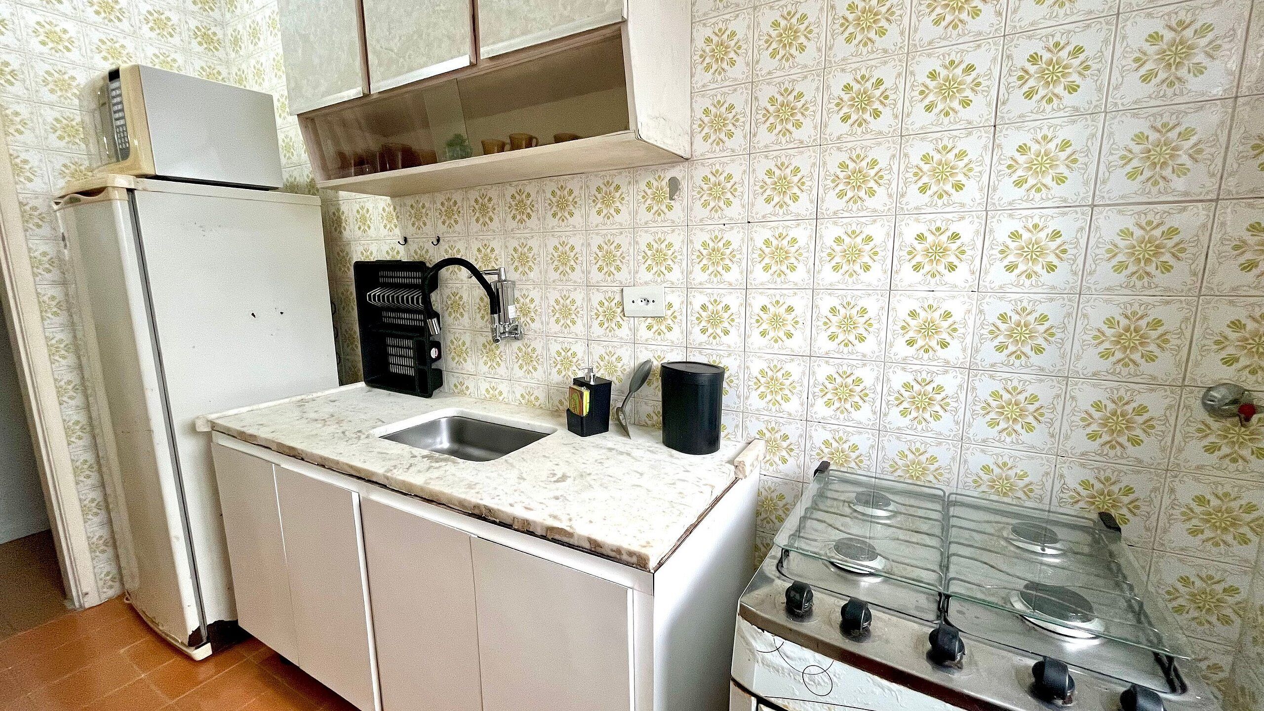 Una cucina compatta con frigorifero, lavello doppio e piano cottura a gas.
