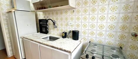 Una cucina compatta con frigorifero, lavello doppio e piano cottura a gas.