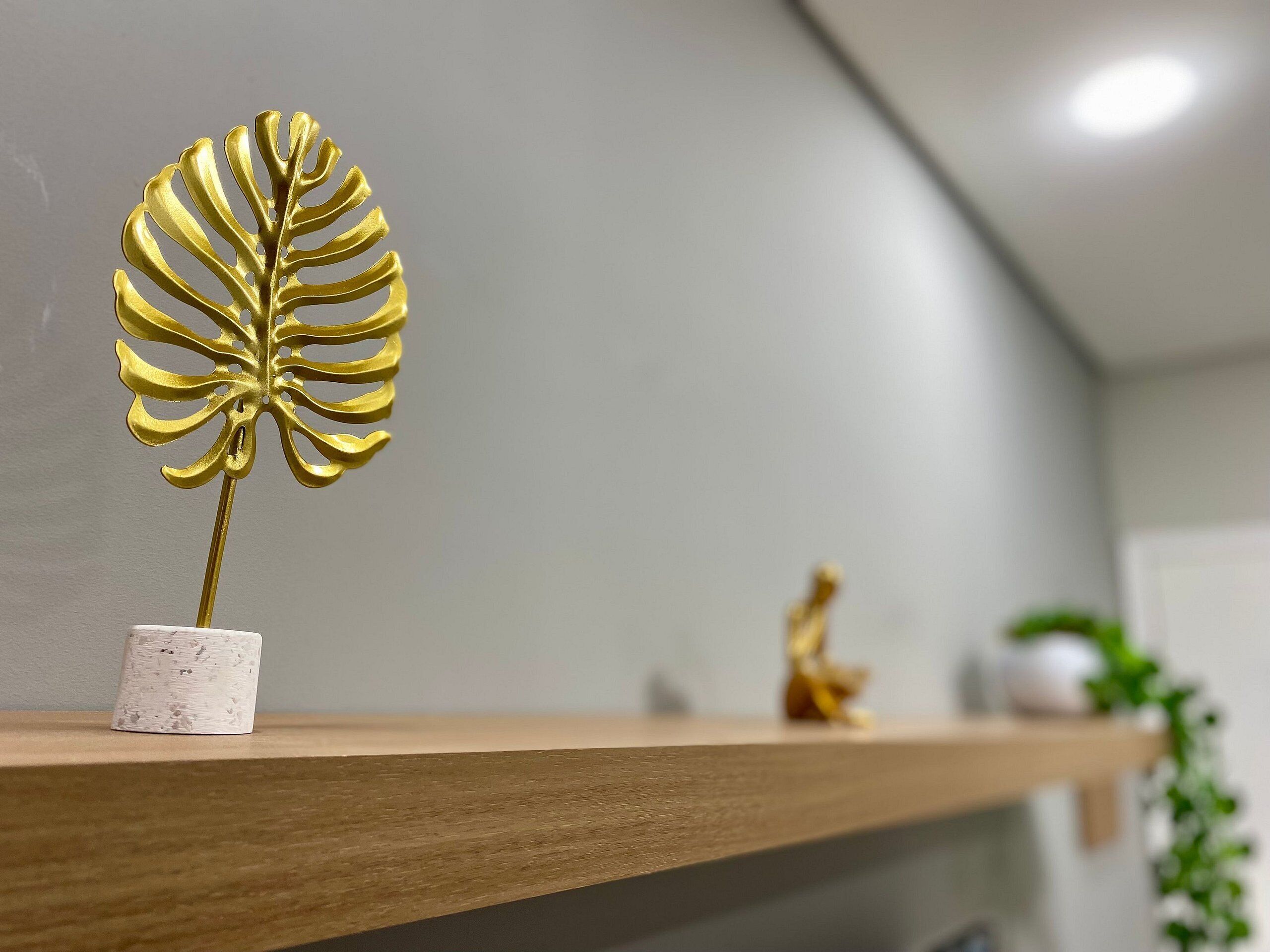Een plank met een gouden decoratief blad en een klein beeldje.