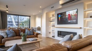 Una sala de estar moderna con sofás de cuero, una mesa de centro y un televisor de pantalla plana sobre una chimenea.