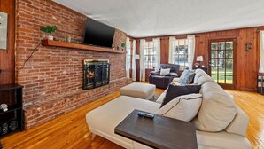 Una sala de estar con chimenea de ladrillo, un televisor de pantalla plana montado encima, un sofá y una mesa de centro.