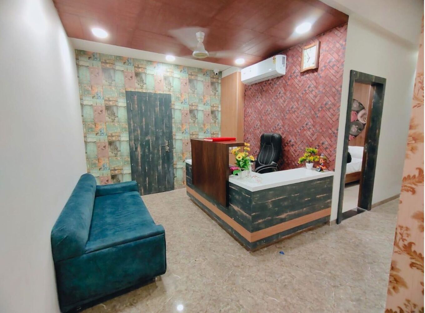 A reception area with a wooden desk, a black office chair, a blue sofa, and a patterned wall.